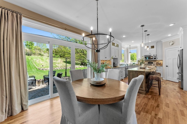 dining room with a chandelier, light wood-style flooring, crown molding, and recessed lighting