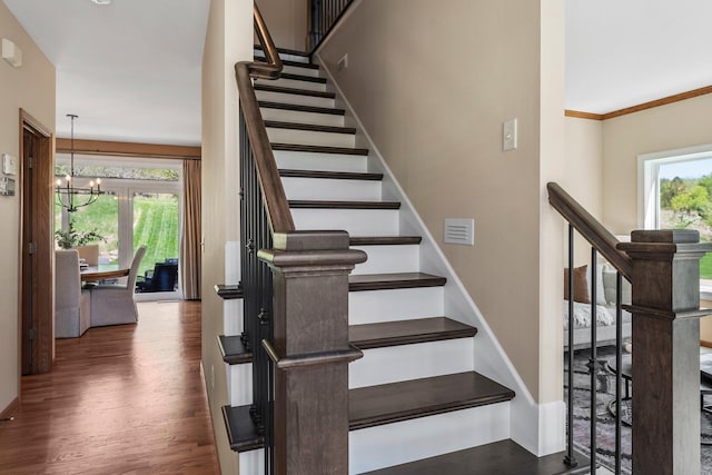 staircase with wood finished floors, a chandelier, and baseboards