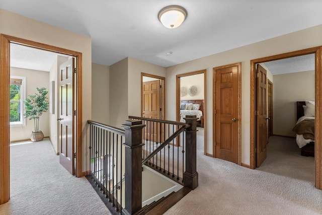 hall with an upstairs landing, carpet, and baseboards