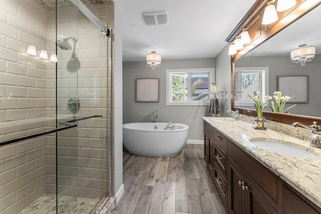 bathroom with a stall shower, a soaking tub, wood finished floors, and double vanity