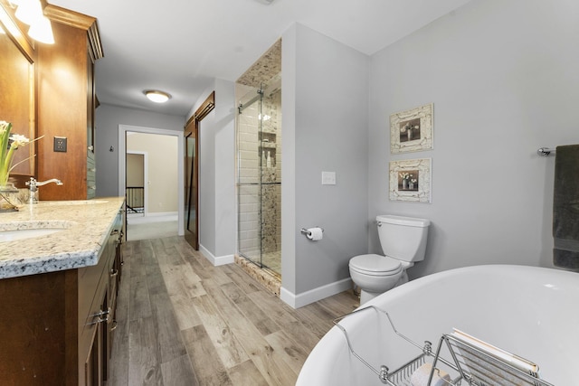 full bathroom with a freestanding tub, wood finished floors, vanity, a stall shower, and toilet