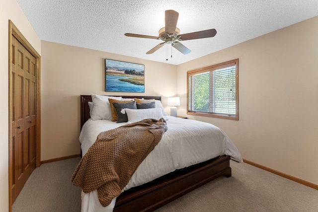 bedroom with carpet, a closet, a textured ceiling, baseboards, and a ceiling fan
