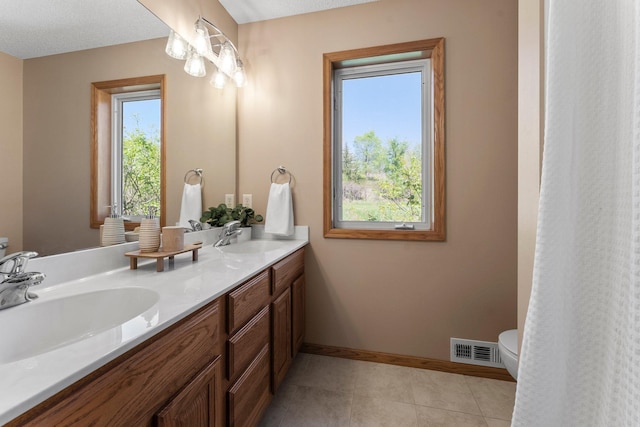 bathroom with toilet, baseboards, double vanity, and tile patterned floors