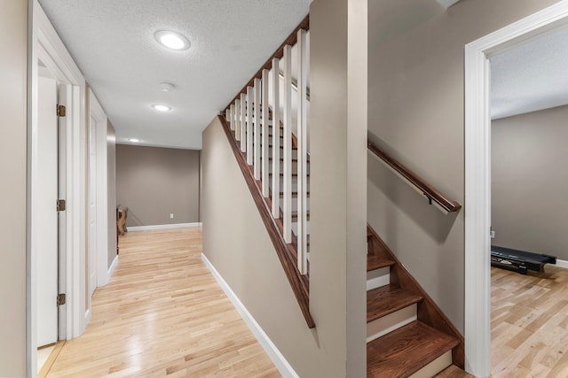 stairs with wood finished floors, a textured ceiling, baseboards, and recessed lighting