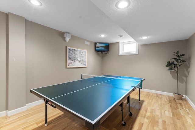recreation room featuring light wood-style floors, baseboards, recessed lighting, and a textured ceiling
