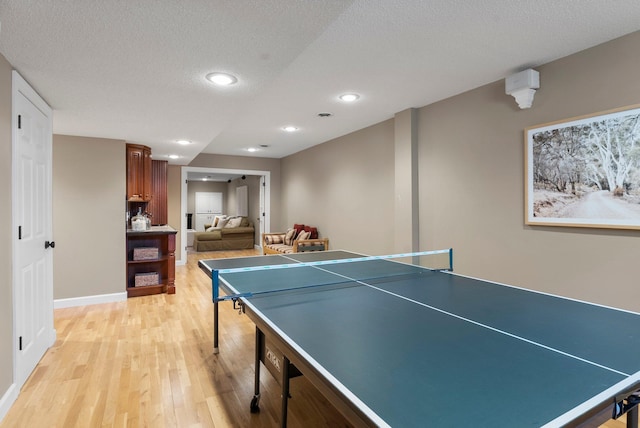 recreation room with light wood-style flooring, recessed lighting, baseboards, and a textured ceiling