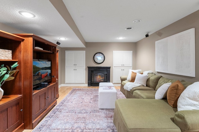 living room featuring light wood-style floors, a glass covered fireplace, and recessed lighting