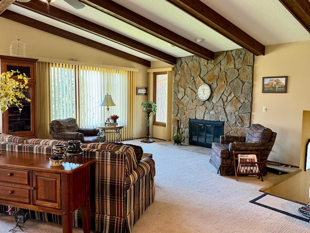 living area with ceiling fan, carpet flooring, a stone fireplace, and vaulted ceiling with beams