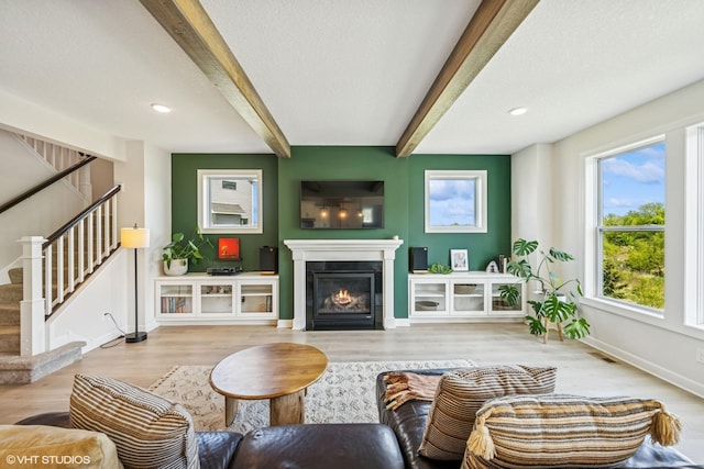 4738 Maas Ct, Minnetrista, MN 55375 - living area with beam ceiling, stairs, baseboards, wood finished floors, and a glass covered fireplace