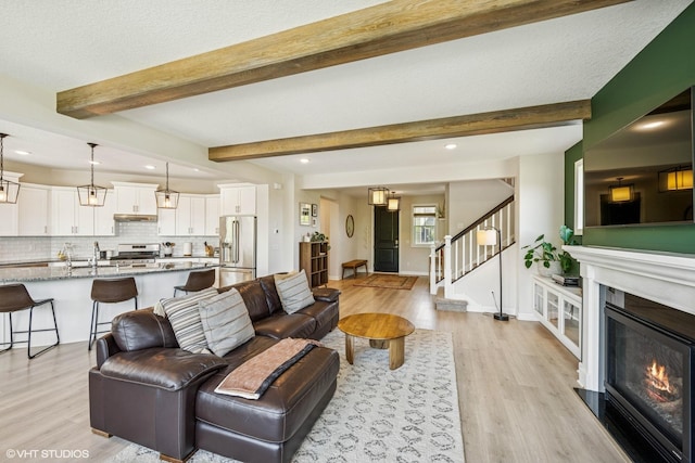 4738 Maas Ct, Minnetrista, MN 55375 - living room featuring light wood-style floors, stairway, recessed lighting, a glass covered fireplace, and baseboards