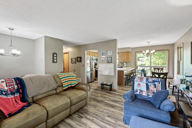 14250 Upper 54th St N, Oak Park Heights, MN 55082 - living area featuring a chandelier, light wood-style floors, a textured ceiling, and baseboards