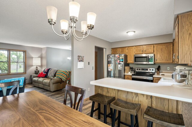14250 Upper 54th St N, Oak Park Heights, MN 55082 - kitchen with stainless steel appliances, light countertops, open floor plan, a peninsula, and brown cabinetry