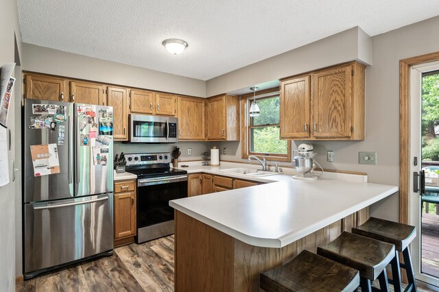 14250 Upper 54th St N, Oak Park Heights, MN 55082 - kitchen featuring appliances with stainless steel finishes, a sink, a peninsula, dark wood-style floors, and light countertops