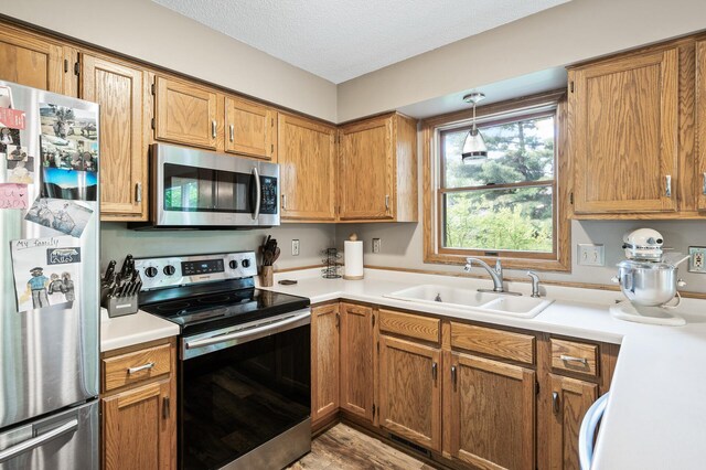 14250 Upper 54th St N, Oak Park Heights, MN 55082 - kitchen with stainless steel appliances, a sink, light countertops, brown cabinetry, and a textured ceiling