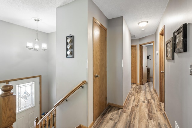 14250 Upper 54th St N, Oak Park Heights, MN 55082 - corridor featuring an upstairs landing, a textured ceiling, light wood finished floors, a chandelier, and baseboards