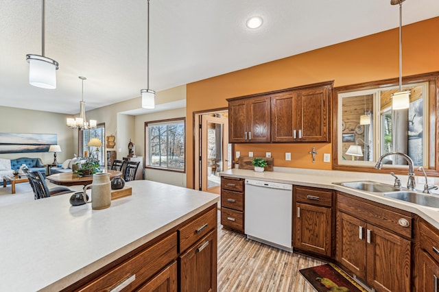 kitchen with white dishwasher, light countertops, plenty of natural light, and a sink