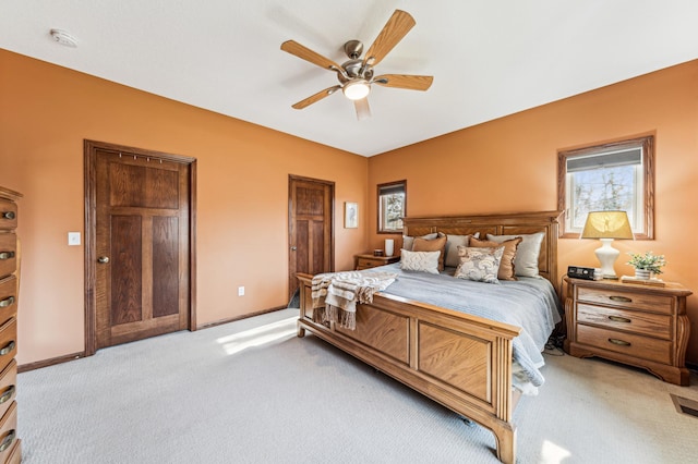 bedroom featuring light colored carpet, baseboards, ceiling fan, and multiple windows
