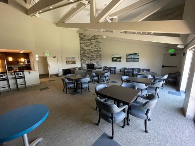 dining area featuring beamed ceiling, high vaulted ceiling, and carpet