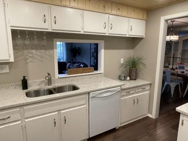 kitchen featuring white dishwasher, a sink, white cabinetry, light stone counters, and dark wood-style floors