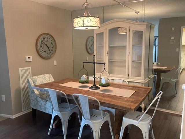 dining room featuring dark wood-style flooring, baseboards, and visible vents
