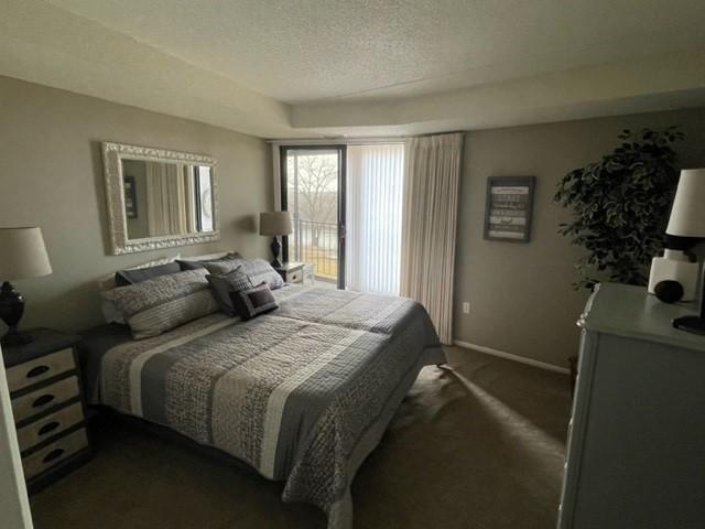 bedroom with a textured ceiling, dark colored carpet, and baseboards