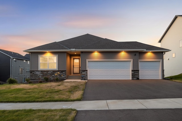 7107 184th St W, Lakeville, MN 55044 - view of front of house with an attached garage, stone siding, driveway, a front lawn, and roof with shingles