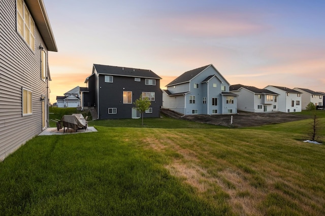 7107 184th St W, Lakeville, MN 55044 - back of house at dusk featuring a yard, a patio area, and a residential view