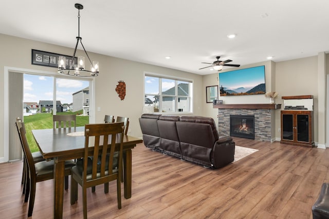 7107 184th St W, Lakeville, MN 55044 - dining room featuring light wood-style flooring, a chandelier, a stone fireplace, recessed lighting, and a ceiling fan