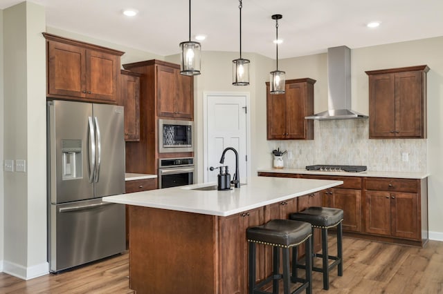 7107 184th St W, Lakeville, MN 55044 - kitchen featuring appliances with stainless steel finishes, wall chimney exhaust hood, a sink, light wood-style floors, and recessed lighting