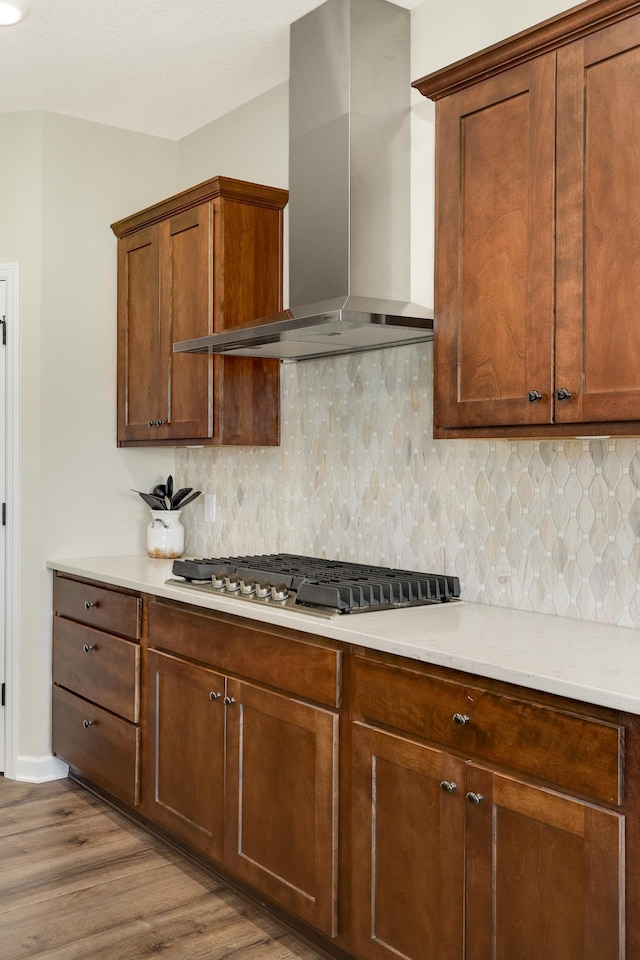7107 184th St W, Lakeville, MN 55044 - kitchen with wall chimney exhaust hood, stainless steel gas cooktop, wood finished floors, light countertops, and tasteful backsplash