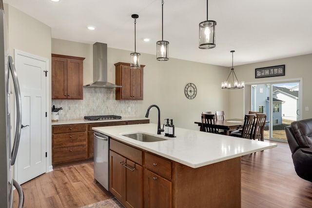 7107 184th St W, Lakeville, MN 55044 - kitchen with wall chimney exhaust hood, stainless steel appliances, a sink, light wood-style floors, and tasteful backsplash