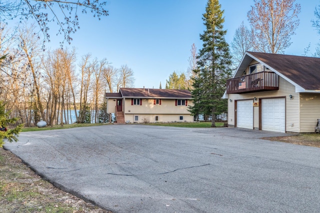 view of side of home with a balcony, aphalt driveway, and a garage