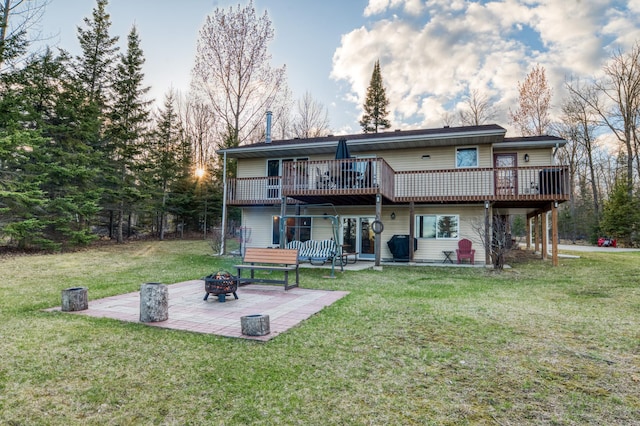back of house featuring a yard, a deck, a patio, and a fire pit