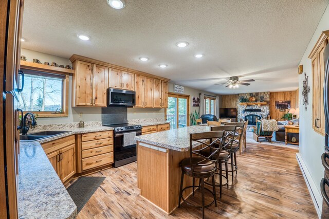 kitchen with a textured ceiling, electric range oven, a sink, and stainless steel microwave