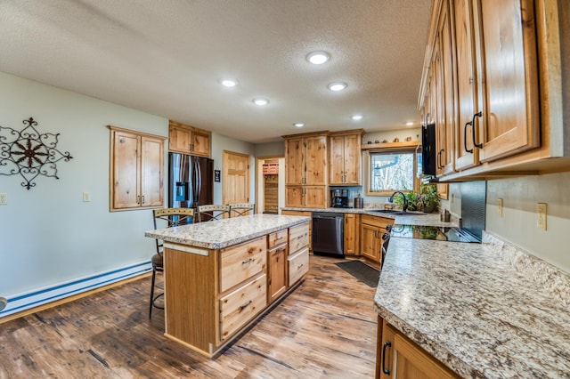 kitchen with a sink, a kitchen breakfast bar, a textured ceiling, dishwashing machine, and stainless steel fridge