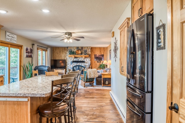 kitchen featuring a ceiling fan, freestanding refrigerator, a textured ceiling, baseboard heating, and light countertops