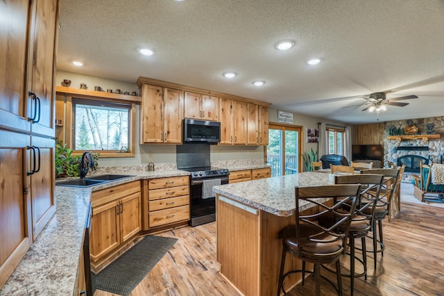 kitchen featuring stainless steel microwave, a textured ceiling, a sink, and range with electric cooktop