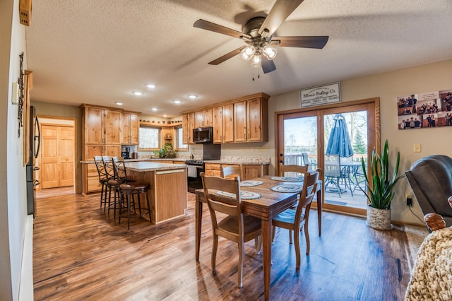 dining room featuring light wood-style flooring, a textured ceiling, baseboards, ceiling fan, and recessed lighting