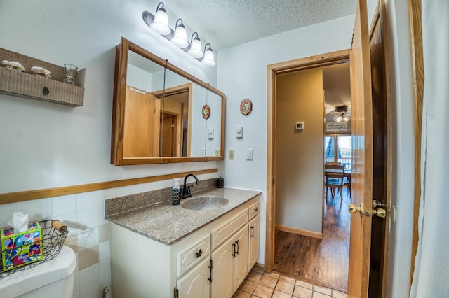 bathroom featuring toilet, tile patterned floors, vanity, and a textured ceiling