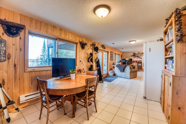 dining area with a textured ceiling, wooden walls, and a baseboard heating unit