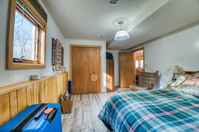 bedroom featuring multiple windows, light wood finished floors, visible vents, and a textured ceiling