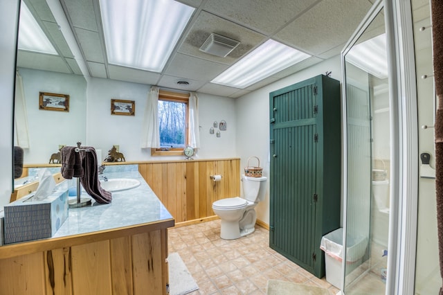 bathroom featuring toilet, a paneled ceiling, visible vents, wood walls, and vanity