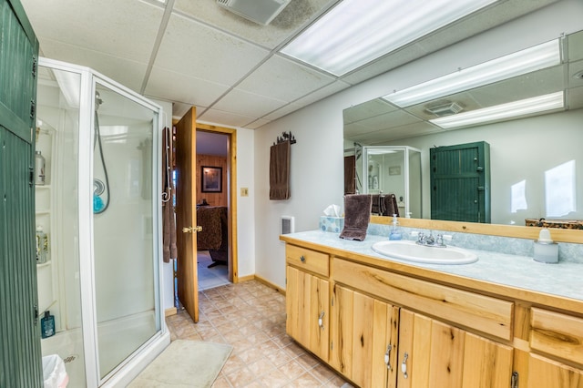 ensuite bathroom featuring ensuite bathroom, vanity, tile patterned floors, a stall shower, and a drop ceiling
