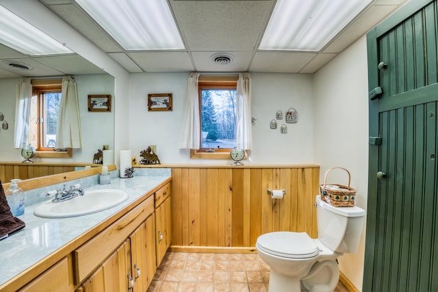 bathroom with toilet, visible vents, vanity, and a paneled ceiling