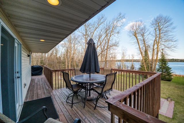 wooden deck with a yard, outdoor dining area, and a water view
