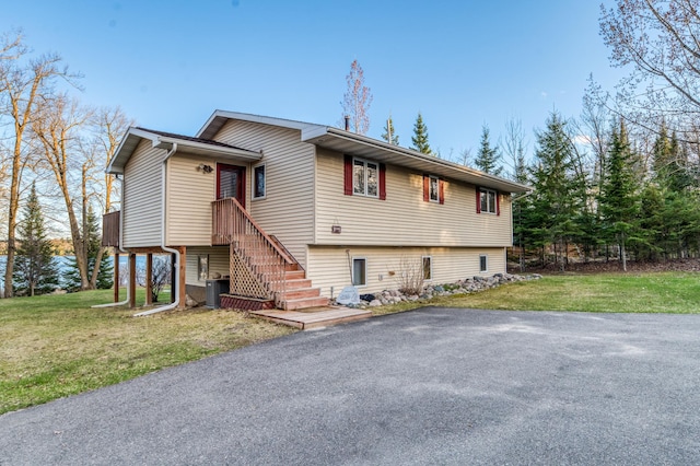 view of front of property featuring central air condition unit, stairs, and a front yard