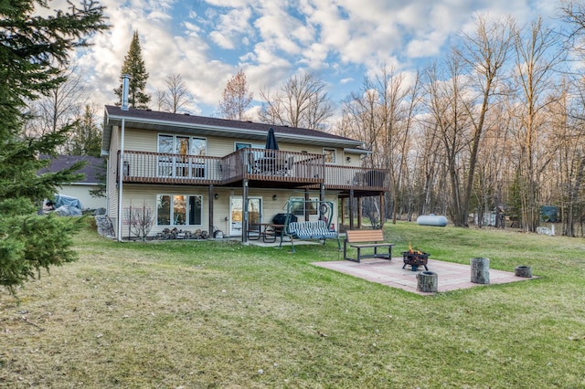 rear view of property featuring a yard, a patio area, a wooden deck, and a fire pit