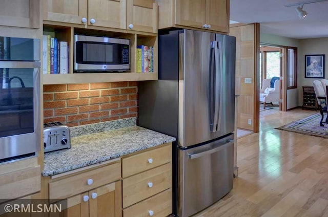 802 Flos Ct, Lincoln Twp, WI 54001 - kitchen featuring appliances with stainless steel finishes, light wood-style flooring, tasteful backsplash, light stone countertops, and rail lighting