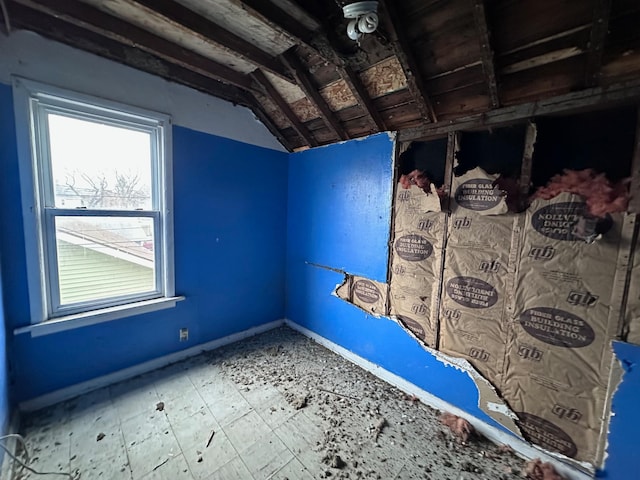 unfurnished bedroom with lofted ceiling and baseboards