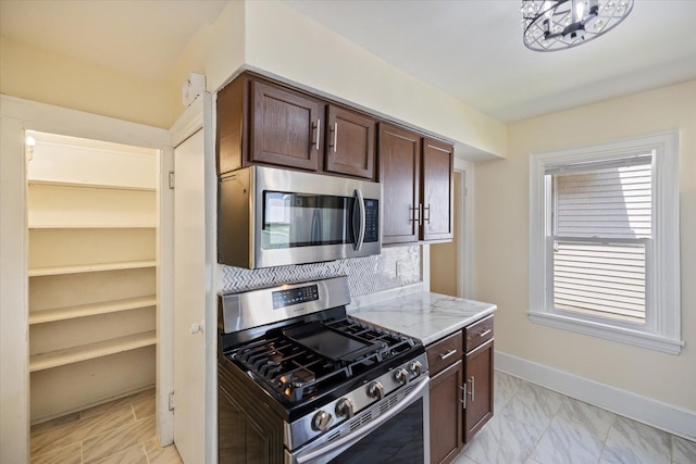 kitchen with stainless steel appliances, dark brown cabinets, decorative backsplash, light stone countertops, and baseboards